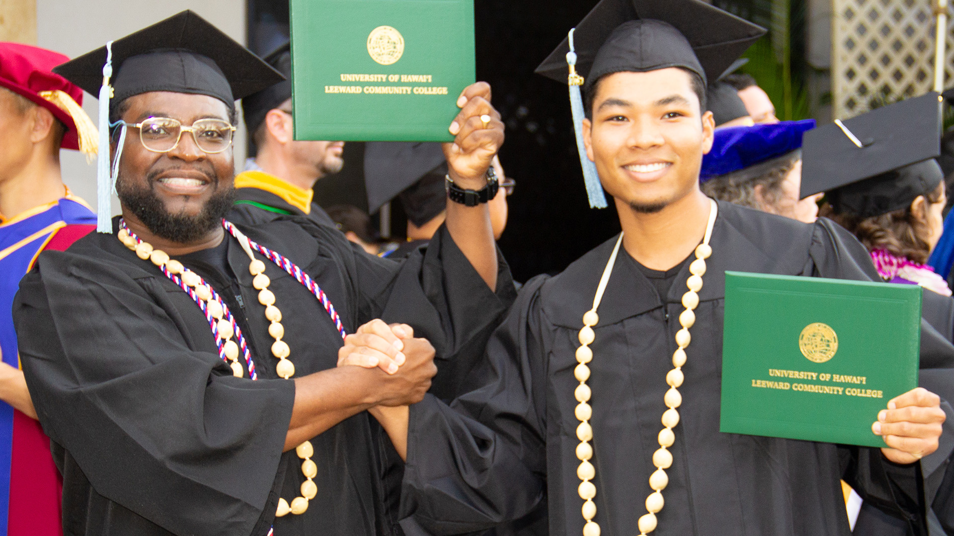 Two male graduates with diplomas