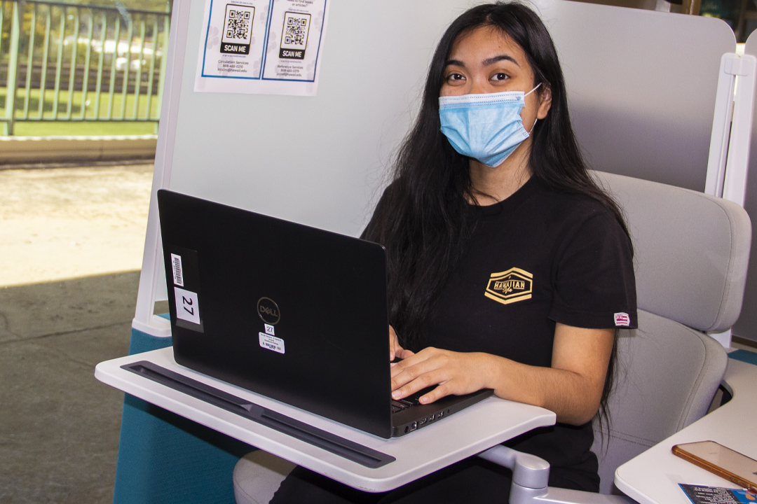 student studying in library with laptop