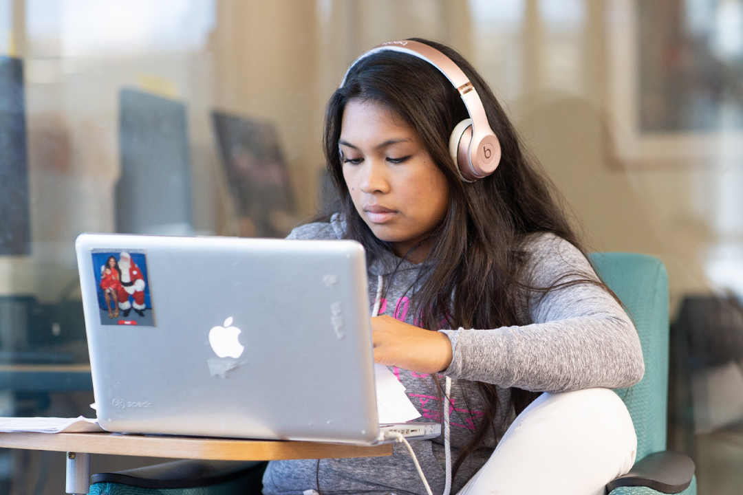 Female student in library with headphones on