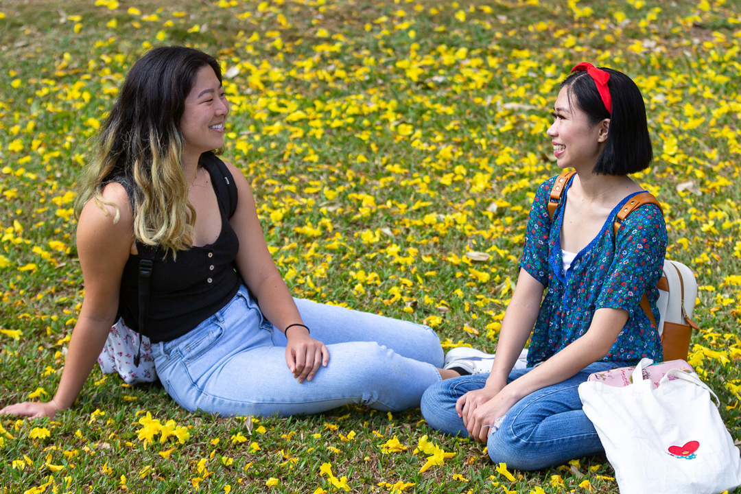 two female students sitting on lawn talking