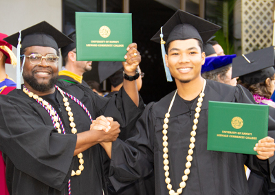 two male students showing their diplomas at graduation