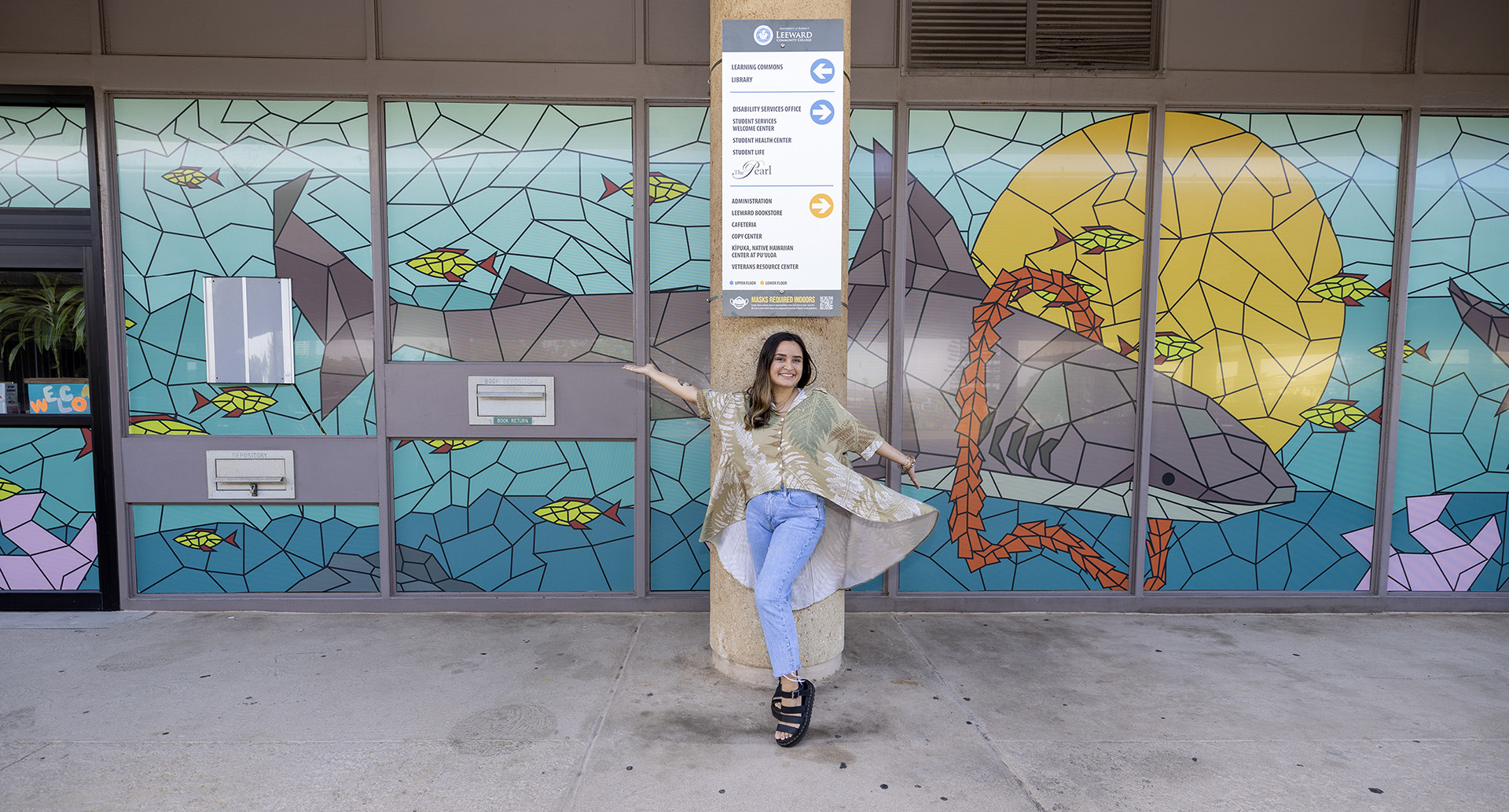 Taylor Wilson in front of her mural at Learning Commons, Nā Kiaʻi o Puʻuloa (The Protectors of Puʻuloa)